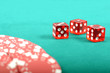 Poker gambling chips and few red dices on a green playing table
