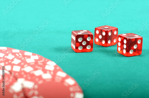 Photo: Poker gambling chips and few red dices on a green playing table Poker gambling chips and few red dices on a green playing table
