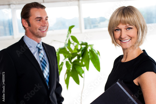 Photo: Handsome boss passing by smiling female colleague Handsome boss passing by smiling female colleague