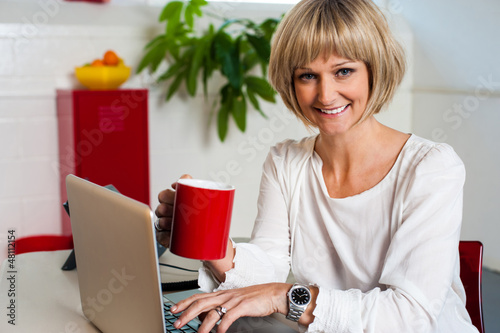 Photo: Cheerful woman holding coffee mug and working Cheerful woman holding coffee mug and working