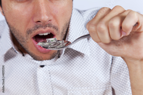 Photo: Man eating little dollar banknote Man eating little dollar banknote