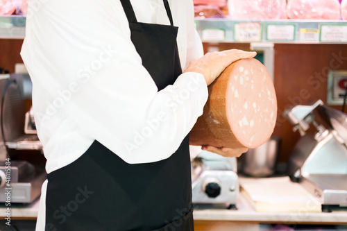 Photo: Shopkeeper showing bologna in an italian grocery store Shopkeeper showing bologna in an italian grocery store