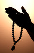male hands with rosary, on brown background