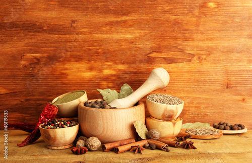 Photo: mortar, bowls and spoons with spices, on wooden background mortar, bowls and spoons with spices, on wooden background