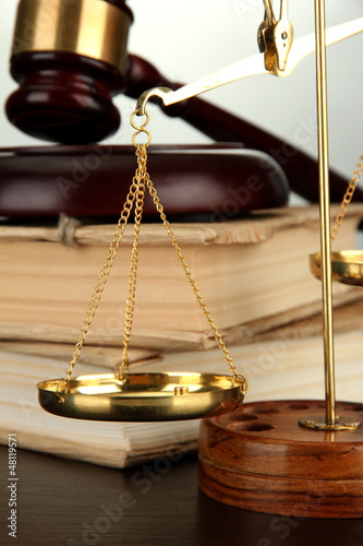 Photo: Golden scales of justice, gavel and books on grey background Golden scales of justice, gavel and books on grey background