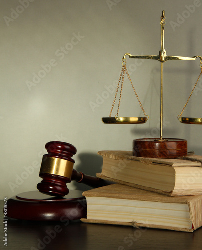 Photo: Golden scales of justice, gavel and books on grey background Golden scales of justice, gavel and books on grey background