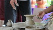 A potters guiding a child to work with the ceramic wheel