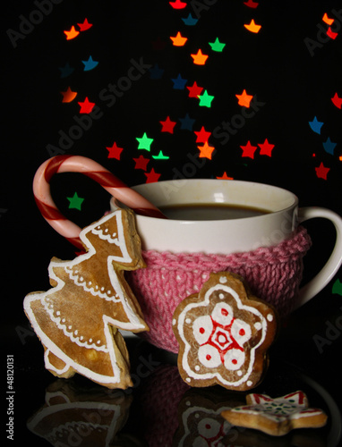 Photo: Cup of coffee with holiday candy on Christmas lights background Cup of coffee with holiday candy on Christmas lights background