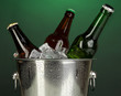 Beer bottles in ice bucket on darck green background