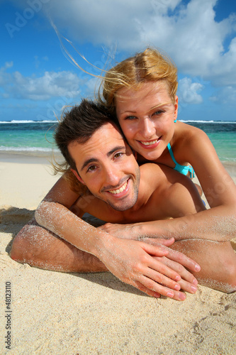 Photo: Cheerful young couple laying on a sandy beach Cheerful young couple laying on a sandy beach