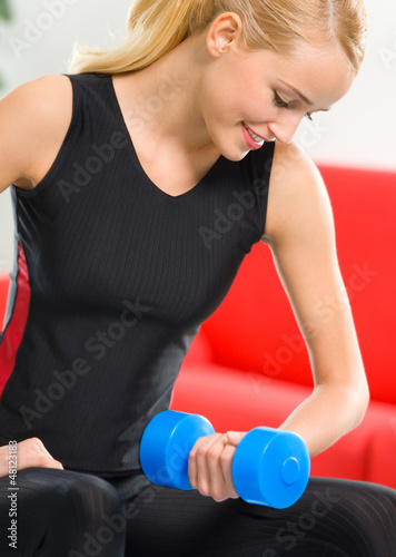 Photo: Young happy smiling woman with dumbbells, indoors Young happy smiling woman with dumbbells, indoors