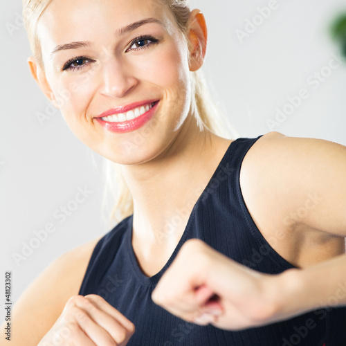 Photo: Young woman doing fitness exercise, indoors Young woman doing fitness exercise, indoors