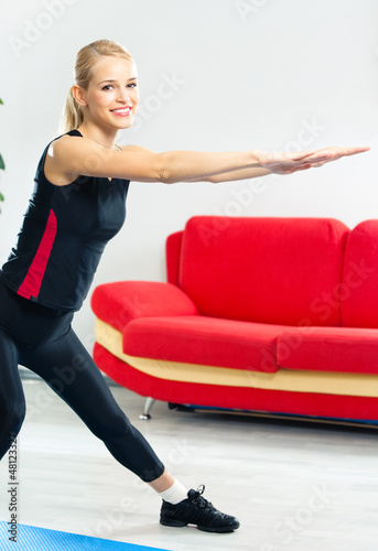 Photo: Young woman doing fitness exercise, indoors Young woman doing fitness exercise, indoors
