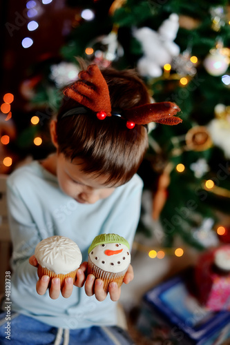 Photo: The boy with small horns of a deer under a New Year tree with be The boy with small horns of a deer under a New Year tree with be