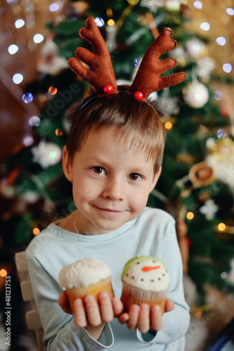 Photo: The boy with small horns of a deer under a New Year tree with be The boy with small horns of a deer under a New Year tree with be