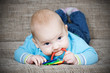 Foto: Happy baby boy lying on his stomach and chew toy. Happy baby boy lying on his stomach and chew toy.