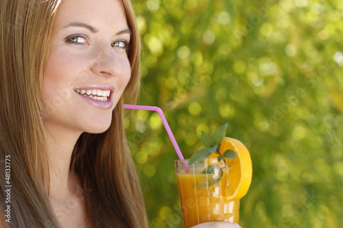 Photo: Junge Frau lächelt mit einem Glas Orangensaft Junge Frau lächelt mit einem Glas Orangensaft
