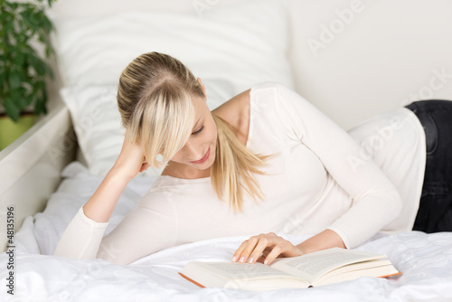 Photo: frau liegt auf dem bett und liest frau liegt auf dem bett und liest