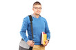 A smiling male student with shoulder bag holding notebooks