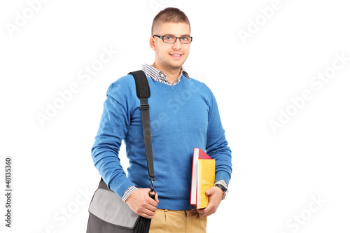 Photo: A smiling male student with shoulder bag holding notebooks A smiling male student with shoulder bag holding notebooks