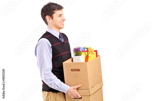 Photo: A smiling male walking with boxes moving into a new home A smiling male walking with boxes moving into a new home