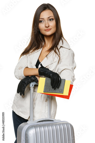 Photo: Female standing with travel bag, holding passport and tickets Female standing with travel bag, holding passport and tickets