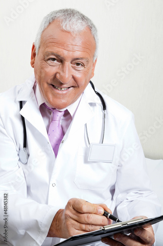 Photo: Doctor Writing On Clipboard Doctor Writing On Clipboard