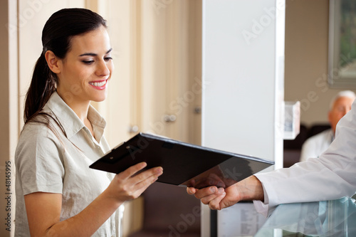 Photo: Receptionist Taking Clipboard From Doctor Receptionist Taking Clipboard From Doctor