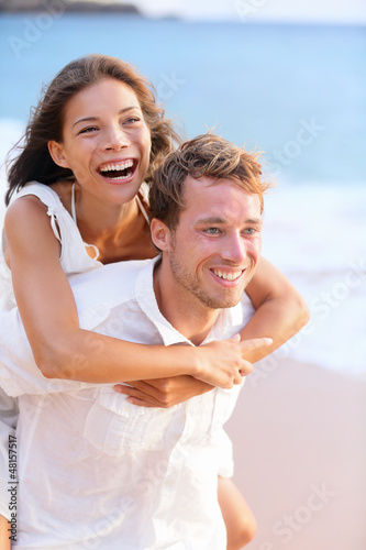 Photo: Happy couple piggybacking on beach. Happy couple piggybacking on beach.