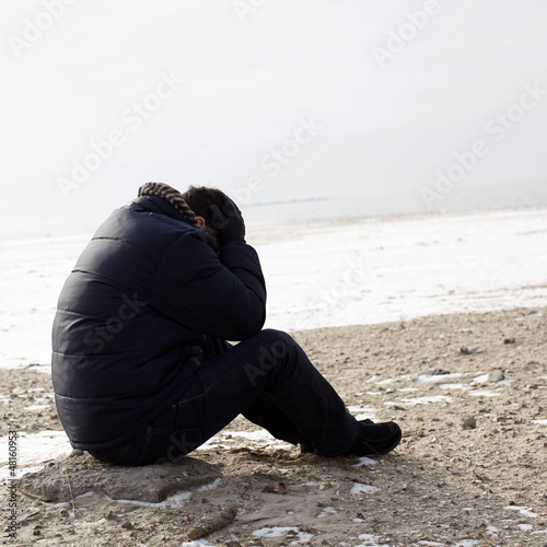 Photo: Lonely man sitting on sand Lonely man sitting on sand