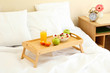 wooden tray with light breakfast on bed