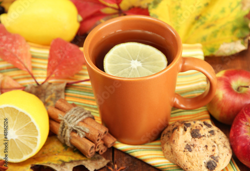 Photo: cup of hot tea and autumn leaves, on wooden table cup of hot tea and autumn leaves, on wooden table