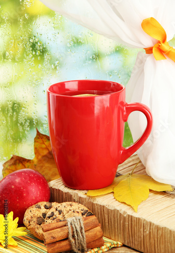 Photo: cup of hot tea and autumn leaves, on rain background cup of hot tea and autumn leaves, on rain background