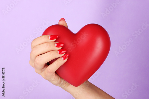 Photo: Red heart in woman's hand on color background Red heart in woman's hand on color background