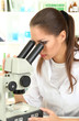 Young scientist looking into  microscope in  laboratory.