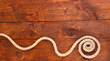 Frame composed of rope on wooden background