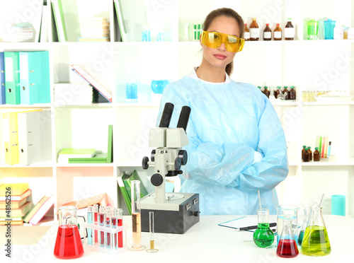 Photo: Young scientist looking into microscope in laboratory. Young scientist looking into microscope in laboratory.