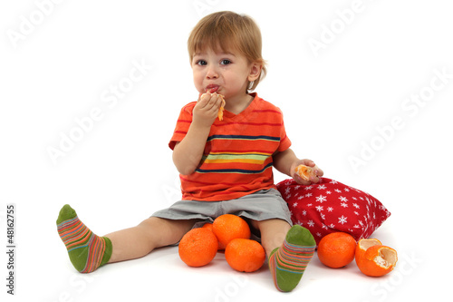 Photo: cute little boy eating tangerines, isolated on white cute little boy eating tangerines, isolated on white