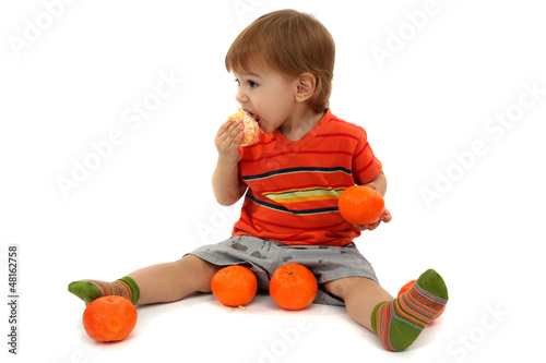 Photo: cute little boy eating tangerines, isolated on white cute little boy eating tangerines, isolated on white