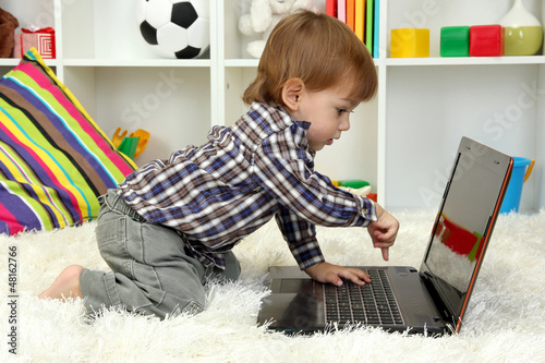 Photo: cute little boy and notebook in room cute little boy and notebook in room