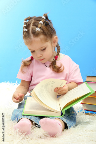 Photo: cute little girl with colorful books, on blue background cute little girl with colorful books, on blue background