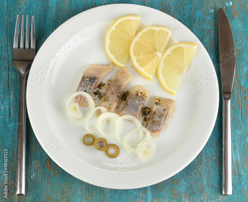 Photo: Dish of herring on plate on blue wooden table close-up Dish of herring on plate on blue wooden table close-up