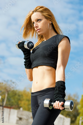 Photo: Beautiful fit woman exercising outdoors over a sky background Beautiful fit woman exercising outdoors over a sky background