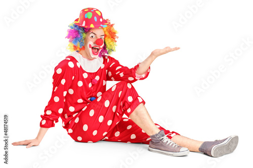 Photo: Clown with smiling joyful expression sitting down and gesturing Clown with smiling joyful expression sitting down and gesturing