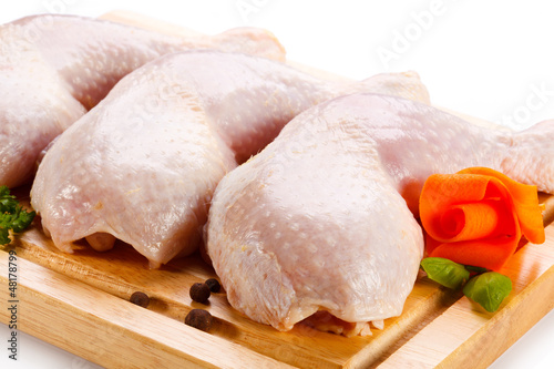 Photo: Raw chicken legs on cutting board on white background Raw chicken legs on cutting board on white background