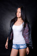 Fashionable Asian girl in a studio in a leather jacket