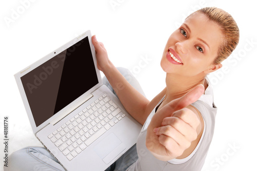 Photo: Young girl with a laptop sitting on the floor, showing ok Young girl with a laptop sitting on the floor, showing ok