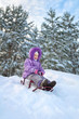 Little girl sledding in the winter day