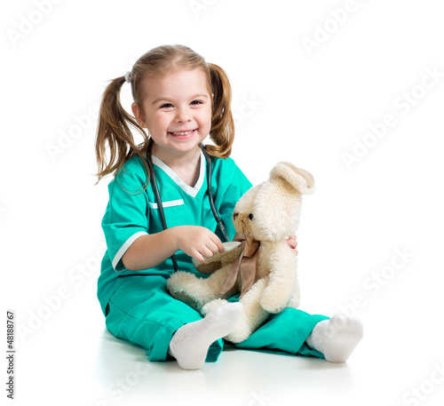 Photo: Adorable girl with clothes of doctor spoon playing with toy over Adorable girl with clothes of doctor spoon playing with toy over