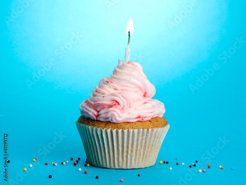 Photo: tasty birthday cupcake with candle, on blue background tasty birthday cupcake with candle, on blue background